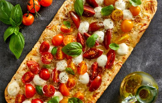 A side view of an artisanal BONICI® Margherita Flatbread topped with fresh Italian ingredients.